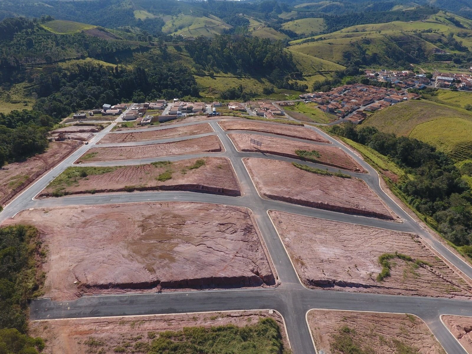 Quadras terraplenadas do Bela Vista com morros e mata ao fundo